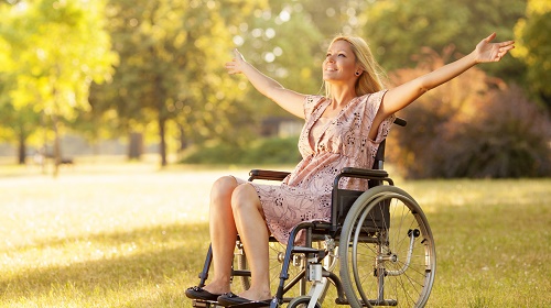 Donna bionda in sedia a rotelle con un sorriso che fa pensare ad una buona fiducia in se stessa